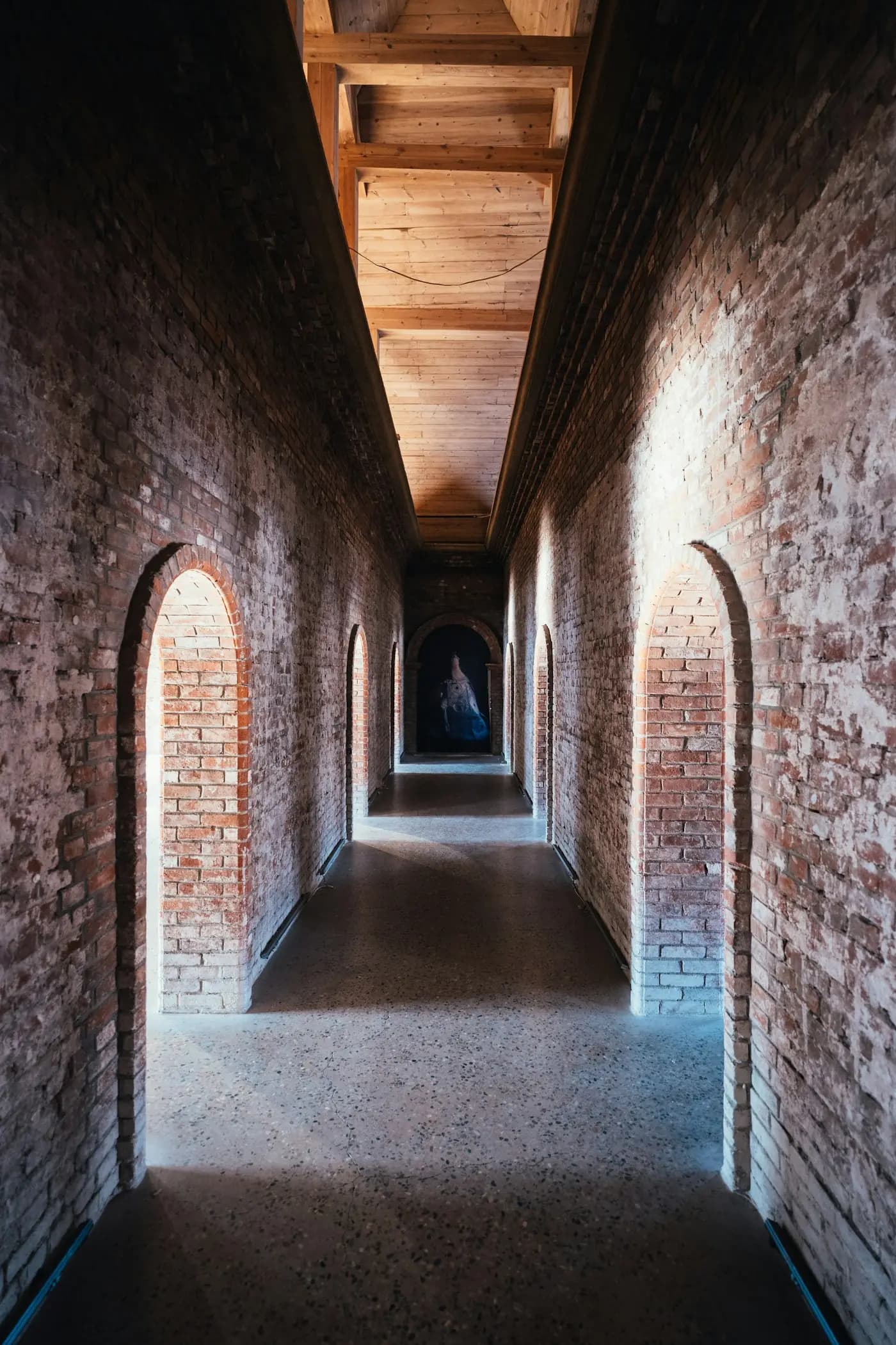 A brick corridor of arched doorways