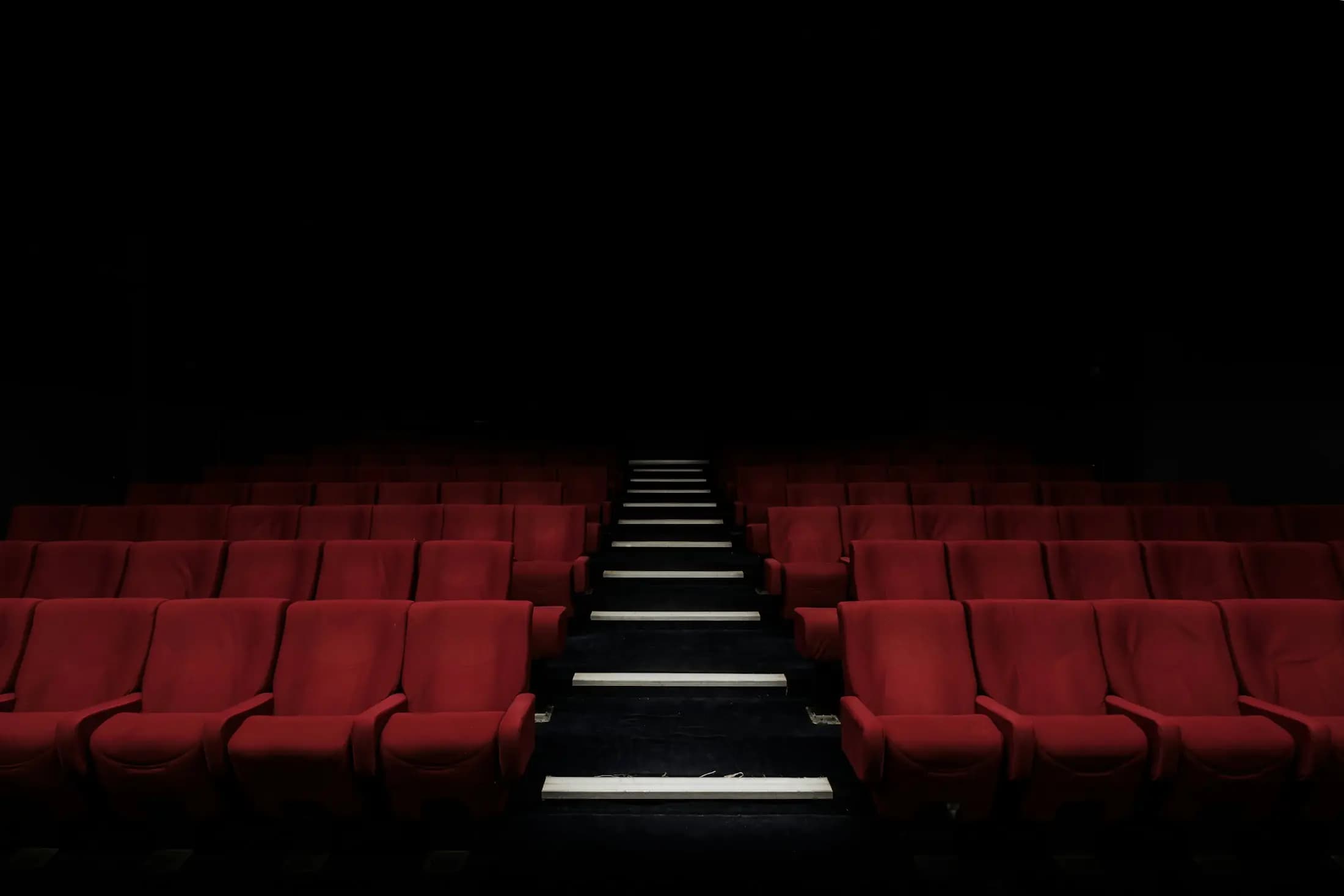 A cinema with red seats, lit along the steps